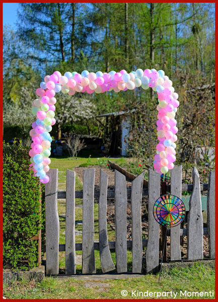 kleine Luftballons bilden eine Girlande über einem Gartentor aus Holz