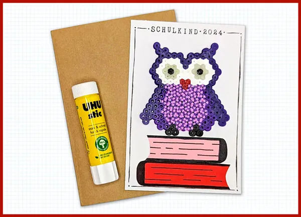 Bügelperlen Eule auf Karte kleben Kartenaufleger mit einer lila Bügelperlen Eule auf einem kleinen Bücherstapel wird mit Klebestift auf eine Karte geklebt.