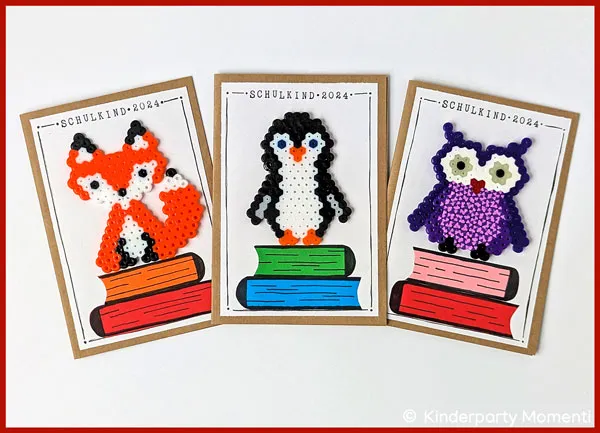 DIY Bügelperlen Einladungskarten zur Einschulung Drei selbsgebastelte Einschulungskarten. Darauf ist jeweils ein kleiner Bücherstapel aus buntem Papier und ein Bügelperlen Tier - Fuchs, Pinguin und Eule