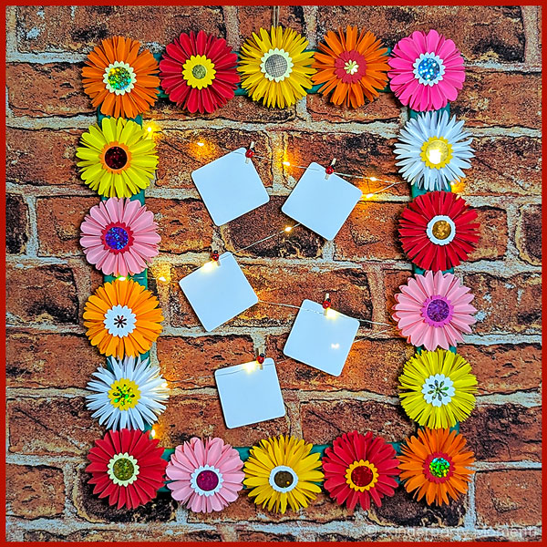 Bilderrahmen aus Papierblumen hängt vor einer Mauer