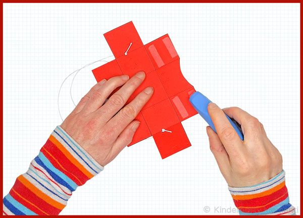 Hände tragen mit Klebroller Kleber auf rote Pappnase auf