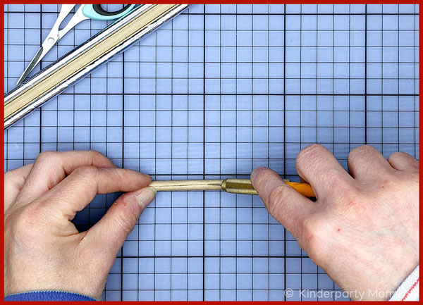 Hände schneiden Papier-Trinkhalm mit einem Bastelmesser auf